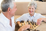 Senior couple sitting on floor playing chess