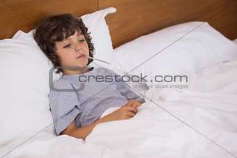 Sick child with thermometer resting in bed