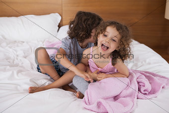 Happy siblings sitting in bed