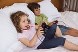 Brother and sister playing video games in bedroom