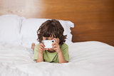 Portrait of a boy with digital camera in bed