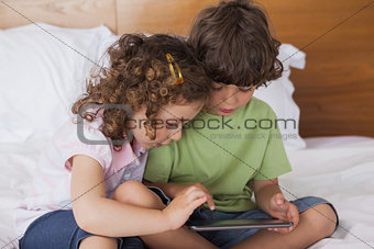 Boy and girl using digital tablet in bed
