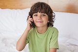 Portrait of young boy using mobile phone in bed