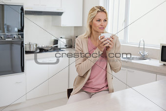 Thoughtful woman drinking coffee in kitchen