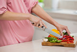 Mid section of a woman chopping vegetables in kitchen