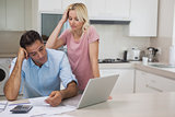 Unhappy couple with bills and laptop in kitchen