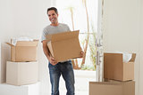 Smiling man carrying boxes in new house