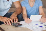 Mid section of a couple with bills and calculator