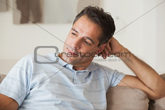 Close-up of a thoughtful man sitting on sofa