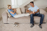 Full length of a relaxed couple sitting in living room