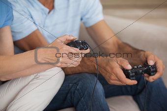 Close-up mid section of couple playing video games