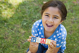 Happy girl holding block alphabets as 'play' at park