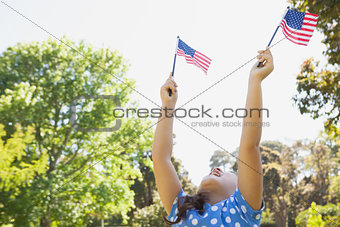 Girl holding up two American flags at park