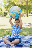 Cute young girl holding globe at park