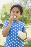 Beautiful girl eating cotton candy at park