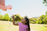 Girl playing with pink balloons at park