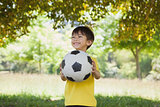 Happy cute little boy with football at park