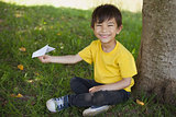Happy boy playing with a paper plane at park