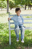Portrait of a happy boy sitting on bench at park