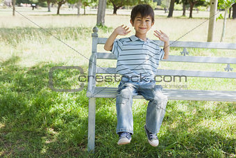 Happy young boy sitting on bench at park
