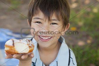 Happy young boy hyolding burger at park