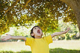 Boy with arms outstretched looking up in park
