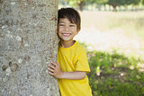 Cheerful boy standing by tree at park