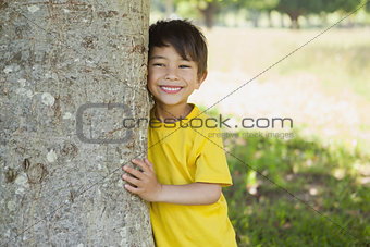 Cheerful boy standing by tree at park
