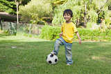 Cute little boy with football standing at park