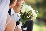 Mid section of a newlywed couple with bouquet in park