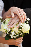 Newlywed couple with wedding rings and bouquet