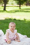 Cute baby sitting on blanket at park