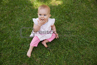 Cute baby sitting on grass at park
