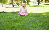 Cheerful cute baby sitting on grass at park