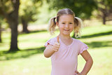 Smiling girl gesturing thumbs up at park