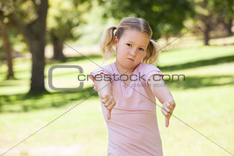 Displeased girl gesturing thumbs down at park