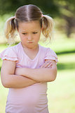 Sad young girl with arms crossed at park