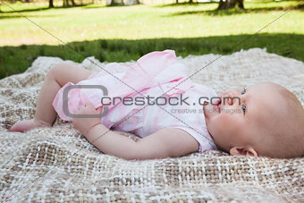 Side view of a cute baby lying on blanket at park