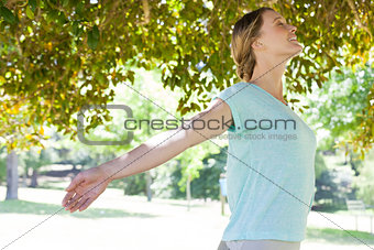 Smiling woman with arms outstretched at park