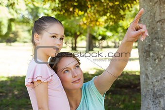 Mother pointing at something besides daughter at park
