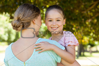 Smiling daughter embracing her mother at park