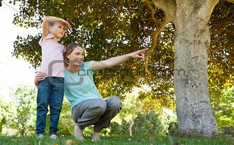Mother pointing out at something besides daughter at park