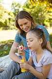 Mother with her daughter blowing soap bubbles at park