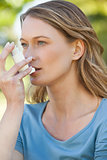 Woman using asthma inhaler in the park