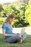 Relaxed young woman using laptop at park