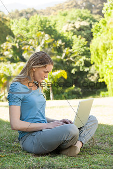 Relaxed young woman using laptop at park