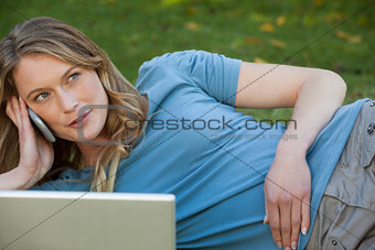 Relaxed woman using laptop and mobile phone at park