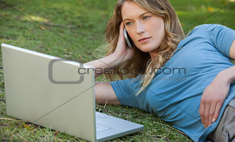 Woman using laptop and mobile phone at park