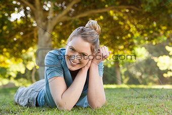 Beautiful relaxed young woman lying on grass at park