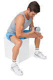 Side view of a fit man exercising with dumbbell